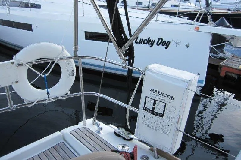 Slide: The Image of 2013 Jeanneau 379 sailboat with lifesaving equipment, docked near "Lucky Dog" boat. - 48