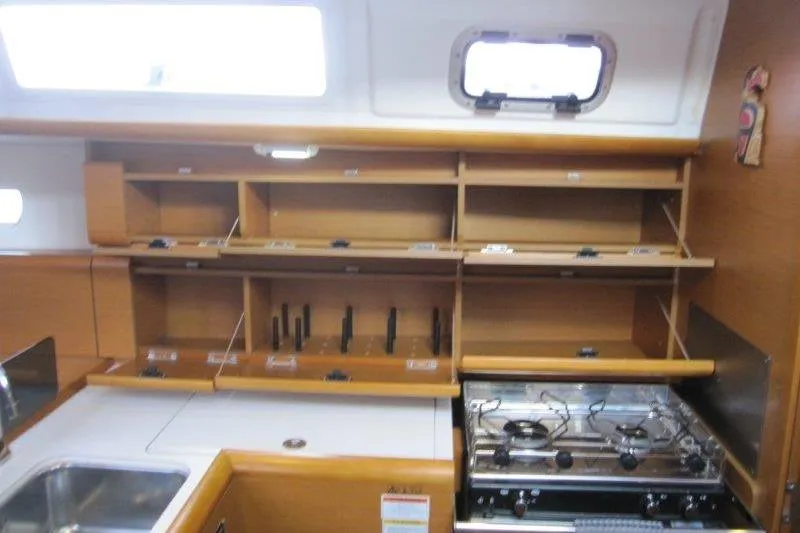Slide: The Image of 2013 Jeanneau 379 yacht kitchen with stove, sink, and wooden storage cabinets. - 7