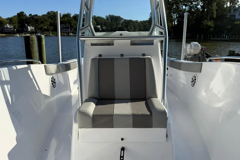 Slide: The Image of 2025 Cape Horn 22 OS boat interior with gray seating, docked by a scenic waterfront. - 5