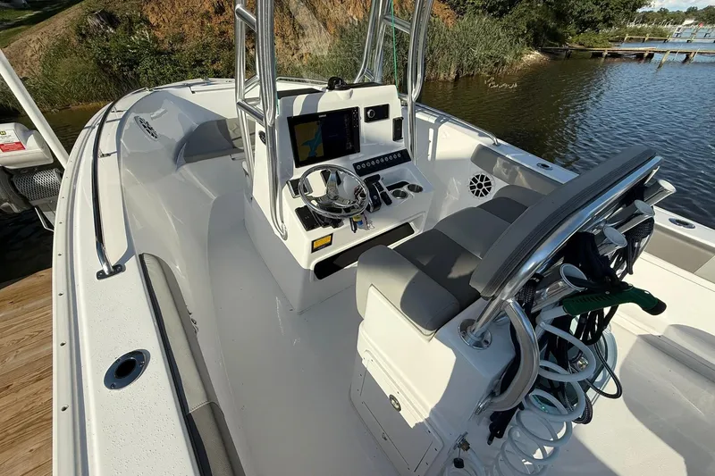 Slide: The Image of 2025 Cape Horn 22 OS boat interior with modern console and seating, docked by a scenic lake. - 9