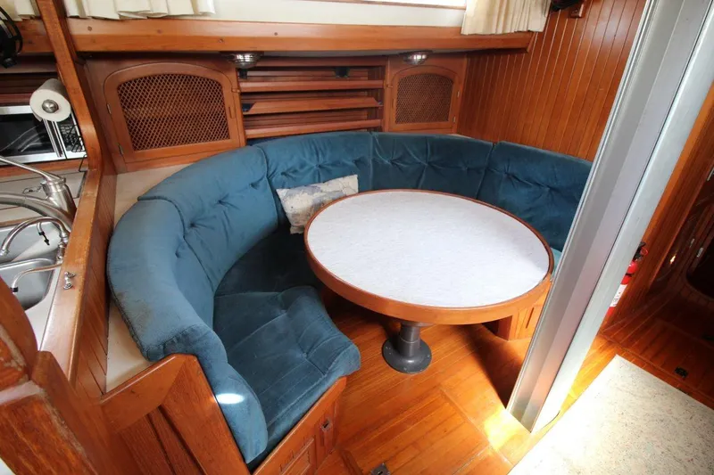 Slide: The Image of 1987 Slocum 43 yacht interior with blue cushioned seating and round table. - 23