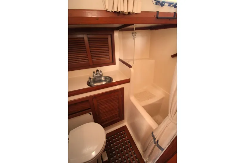 Slide: The Image of 1987 Slocum 43 yacht bathroom with wooden accents, sink, toilet, and shower area. - 28