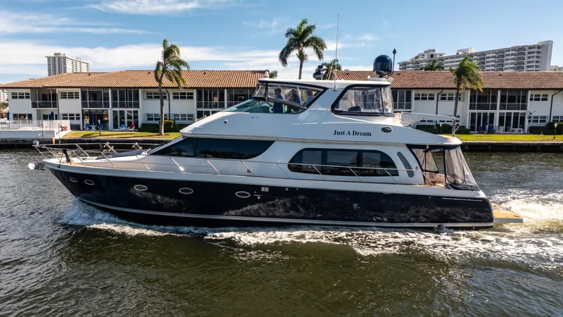 Slide: The Image of 2005 Carver 56 Voyager yacht cruising on a sunny day near waterfront buildings. - 11