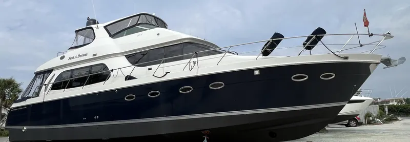 Slide: The Image of 2005 Carver 56 Voyager yacht with sleek design, docked under a cloudy sky. - 14