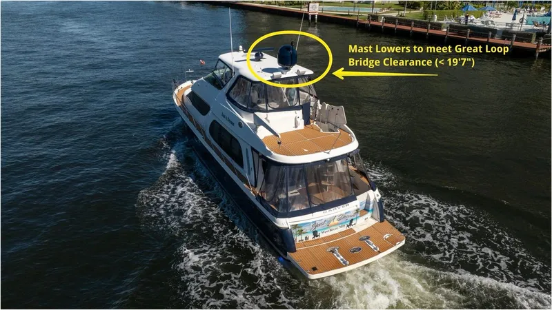 Slide: The Image of 2005 Carver 56 Voyager yacht navigating waterway, featuring adjustable mast for bridge clearance. - 16