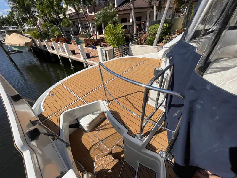 Slide: The Image of 2005 Carver 56 Voyager yacht deck with wooden flooring, docked near waterfront homes. - 37