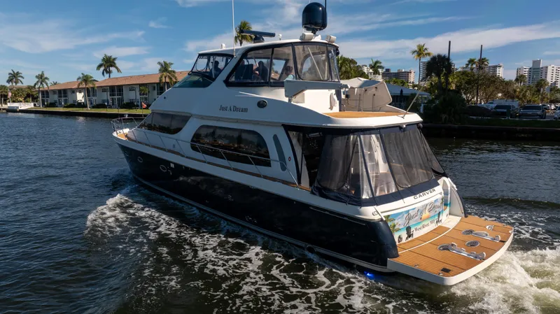 Slide: The Image of 2005 Carver 56 Voyager yacht cruising on a sunny day, surrounded by palm trees. - 9