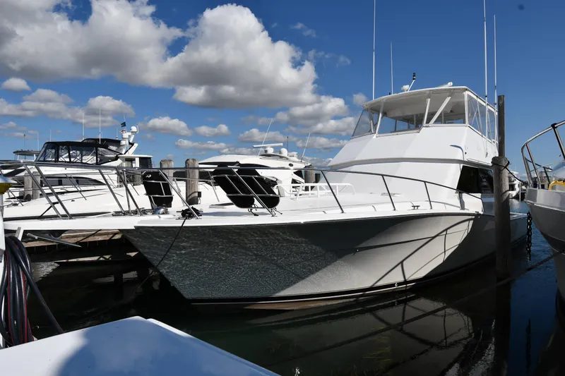 Slide: The Image of 1996 Viking 53 Convertible yacht docked under a blue sky with clouds. - 1