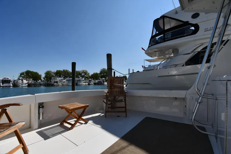 Slide: The Image of 1996 Viking 53 Convertible yacht deck with chairs, overlooking marina and clear blue sky. - 11