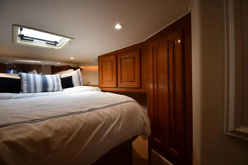Slide: The Image of Cozy bedroom interior of 1996 Viking 53 Convertible yacht with wooden cabinets and skylight. - 41