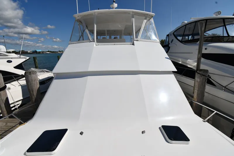 Slide: The Image of 1996 Viking 53 Convertible yacht docked, showcasing sleek white exterior and clear blue sky. - 6