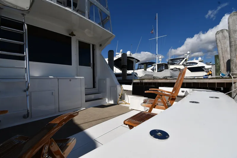 Slide: The Image of 1996 Viking 53 Convertible yacht docked, featuring wooden chairs and a clear blue sky. - 9