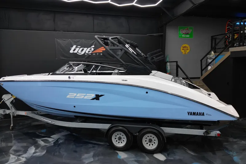 Slide: The Image of 2024 Yamaha Boats 252XE in showroom, blue and white design, on trailer. - 3
