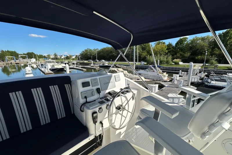 Slide: The Image of 2021 Kadey-Krogen 44AE yacht helm with Garmin navigation, docked in a serene marina. - 43