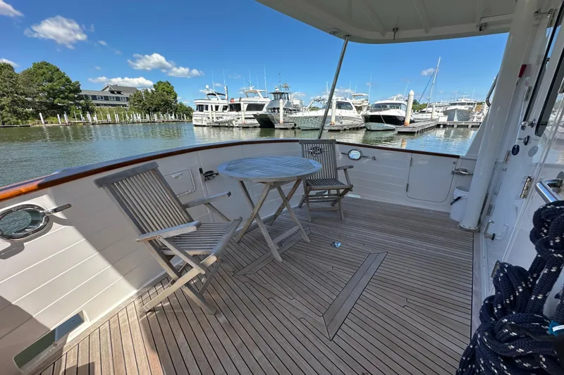 Slide: The Image of Deck of 2021 Kadey-Krogen 44AE yacht with wooden chairs and table, docked at marina. - 59