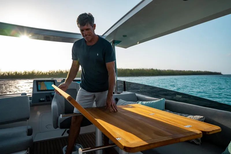 Slide: The Image of Man on 2026 Beneteau Swift Trawler 48, adjusting table, ocean view in background. - 17