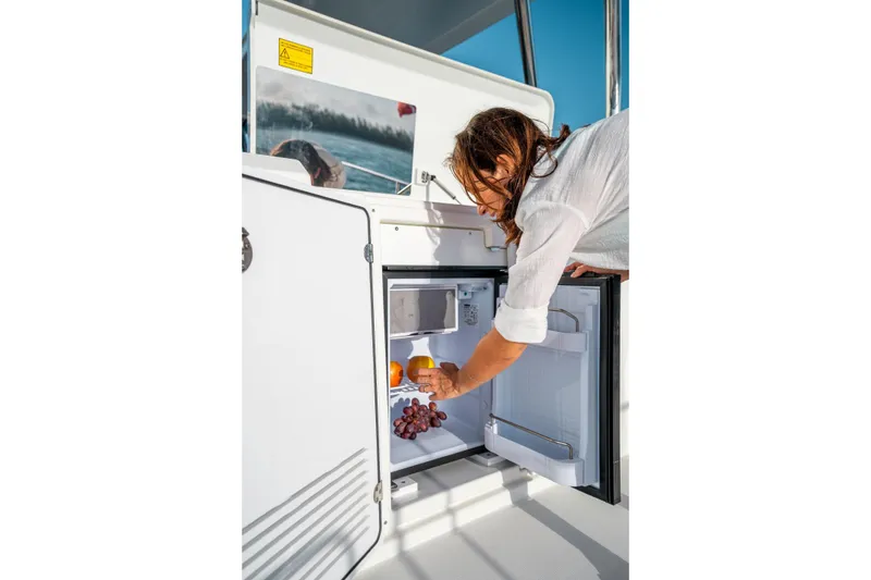 Slide: The Image of Person accessing fridge on 2026 Beneteau Swift Trawler 48 yacht deck. - 18