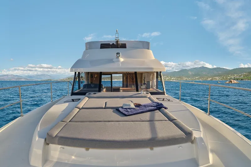 Slide: The Image of 2026 Beneteau Swift Trawler 48 cruising on open sea with scenic coastal backdrop. - 20