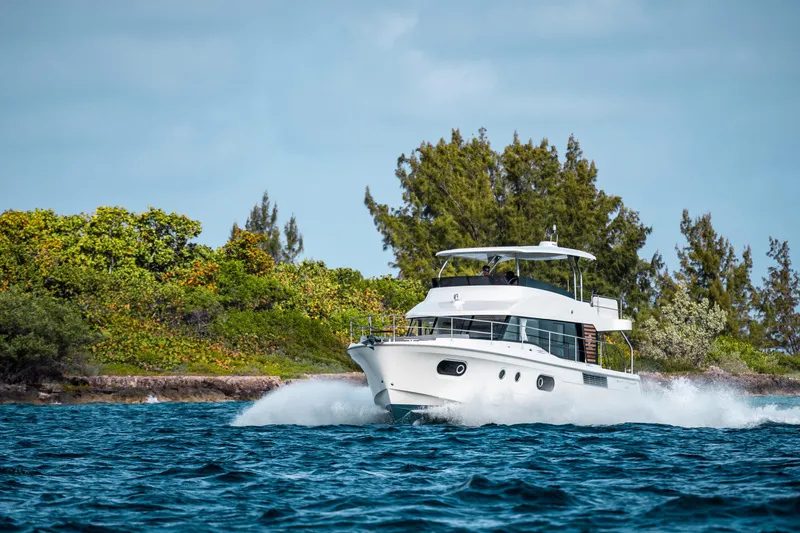 Slide: The Image of 2026 Beneteau Swift Trawler 48 cruising near lush shoreline. - 26