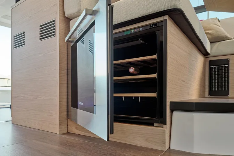 Slide: The Image of 2026 Beneteau Swift Trawler 48 interior with open wine cooler and wooden finish. - 7