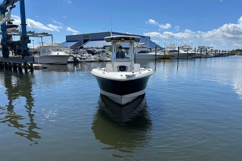 Slide: The Image of 2020 Robalo R230 Center Console boat docked in a marina under a blue sky. - 2