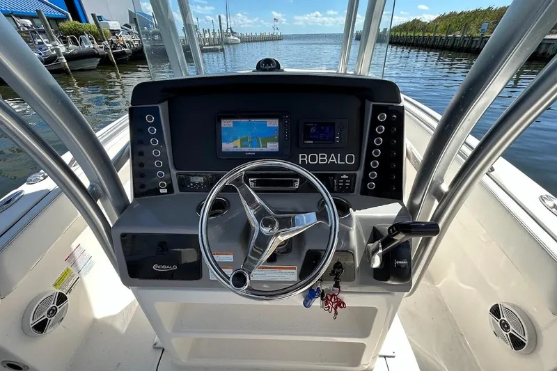 Slide: The Image of 2020 Robalo R230 Center Console boat with white seating at a marina dock. - 5
