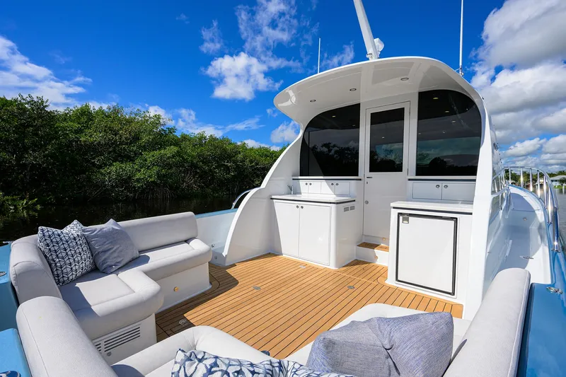 Slide: The Image of 2024 Palm Beach Motor Yachts GT50 deck with seating, blue skies, and lush greenery. - 13