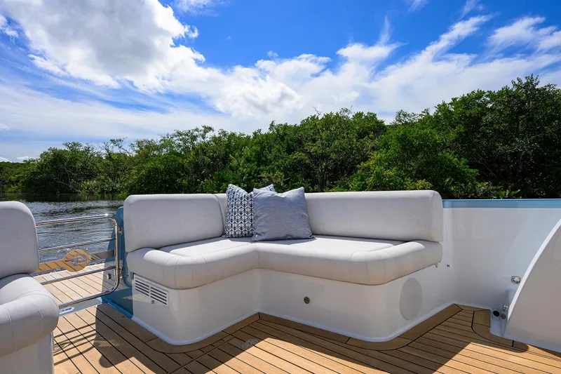 Slide: The Image of 2024 Palm Beach Motor Yachts GT50 deck with cushioned seating, scenic water view. - 19