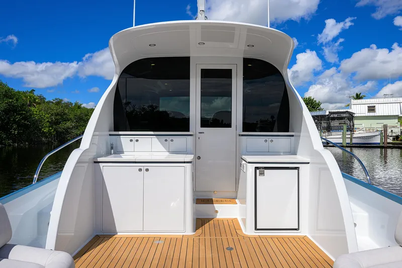 Slide: The Image of 2024 Palm Beach Motor Yachts GT50, sleek deck design, modern cabinetry, and scenic waterway backdrop. - 20