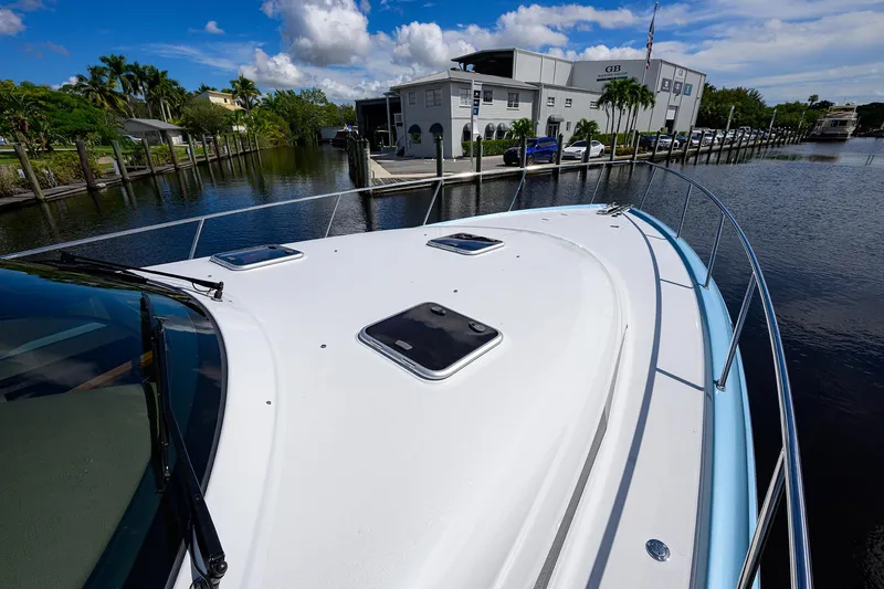Slide: The Image of 2024 Palm Beach Motor Yachts GT50 docked by a waterfront building under a blue sky. - 30
