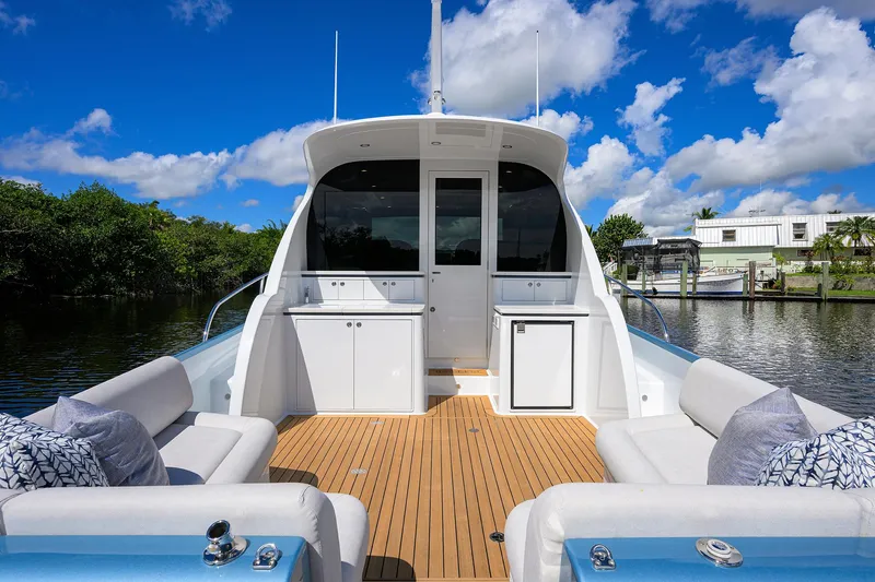 Slide: The Image of 2024 Palm Beach Motor Yachts GT50 with spacious deck, luxurious seating, and scenic waterway backdrop. - 14