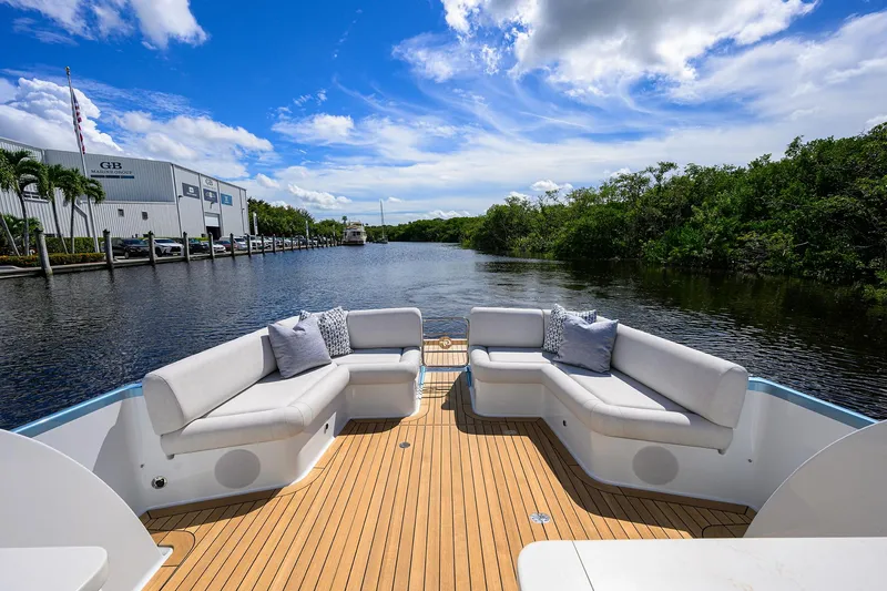 Slide: The Image of 2024 Palm Beach Motor Yachts GT50 deck with luxurious seating, scenic waterway view. - 16