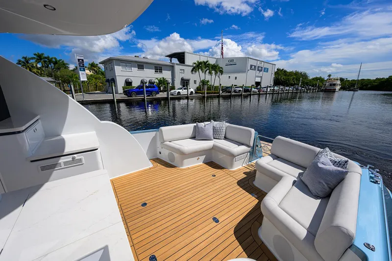Slide: The Image of 2024 Palm Beach Motor Yachts GT50, luxurious deck seating, waterfront view, sunny day. - 17