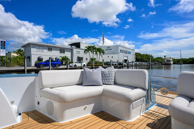 Slide: The Image of 2024 Palm Beach Motor Yachts GT50, luxurious deck seating, marina backdrop, sunny day. - 18