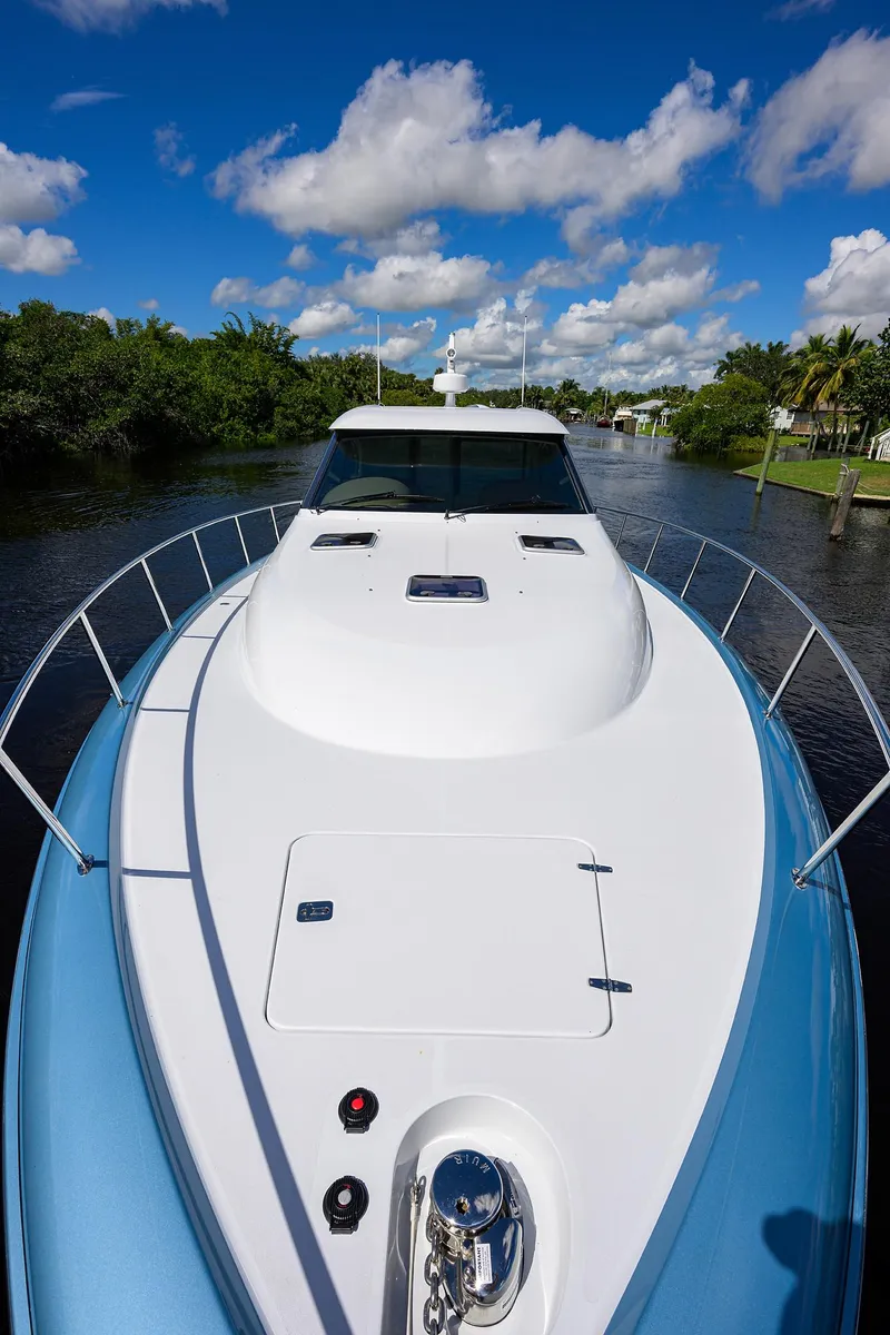 Slide: The Image of 2024 Palm Beach Motor Yachts GT50 cruising on a scenic waterway under a clear blue sky. - 32