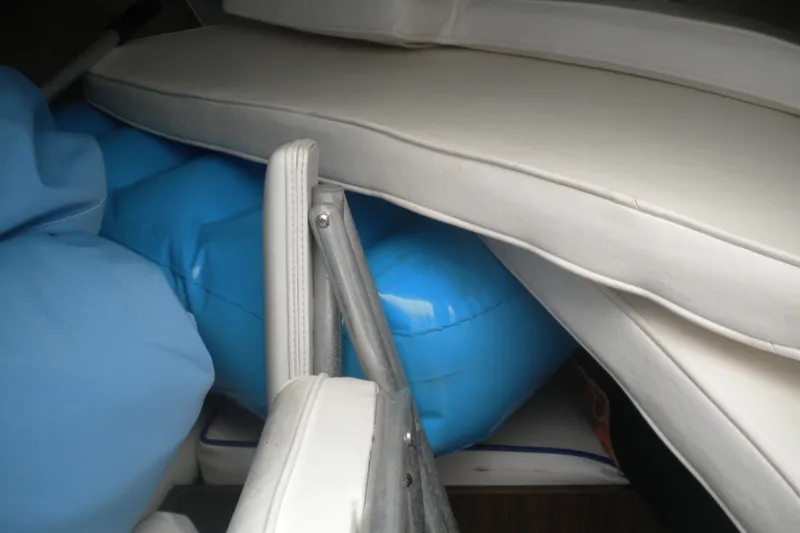 Slide: The Image of 1979 Bertram Flybridge Cruiser interior with stacked cushions and blue inflatable items. - 11