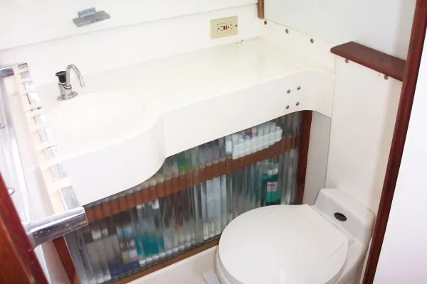 Slide: The Image of 1979 Bertram Flybridge Cruiser bathroom with sink, toilet, and storage shelves. - 12