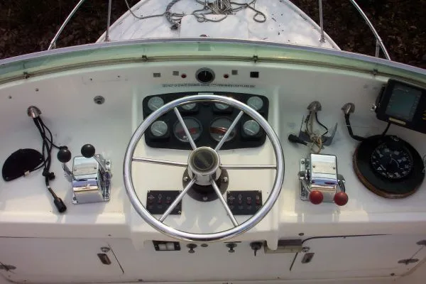 Slide: The Image of 1979 Bertram Flybridge Cruiser helm with steering wheel, gauges, and navigation controls. - 4