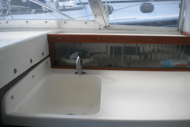 Slide: The Image of 1979 Bertram Flybridge Cruiser sink area with faucet, featuring a sleek design and storage. - 6