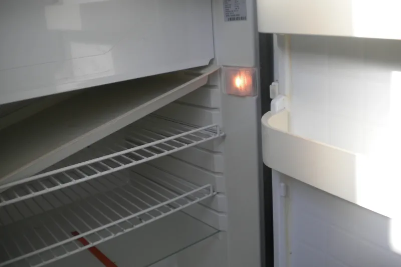 Slide: The Image of Open refrigerator inside a 1979 Bertram Flybridge Cruiser, showing empty shelves and interior light. - 7