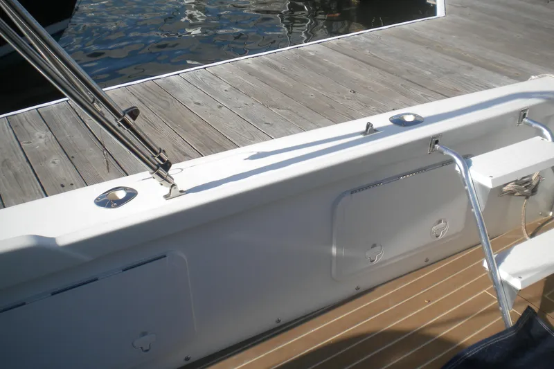 Slide: The Image of 1979 Bertram Flybridge Cruiser boat deck with wooden flooring and dockside view. - 13
