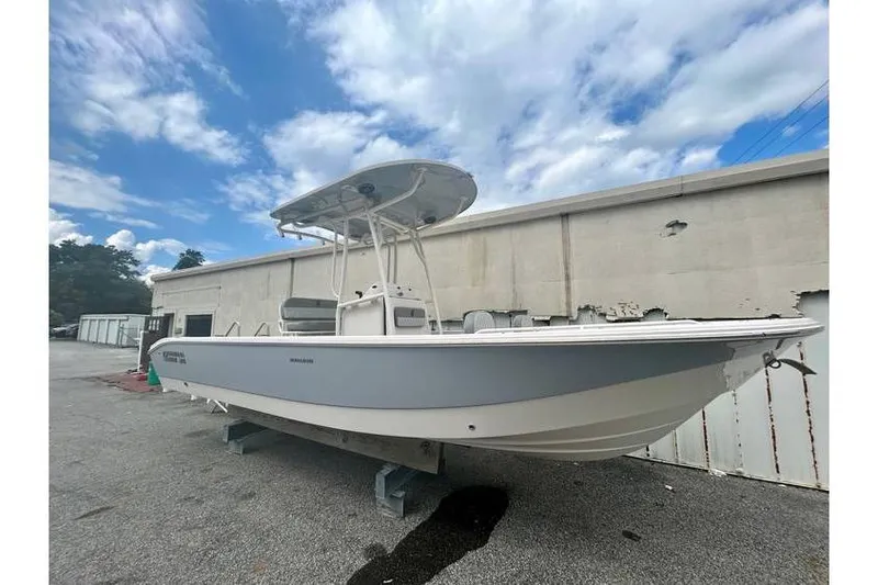 Slide: The Image of 2026 Carolina Skiff 24 Ultra Elite boat on display outdoors, under a partly cloudy sky. - 2
