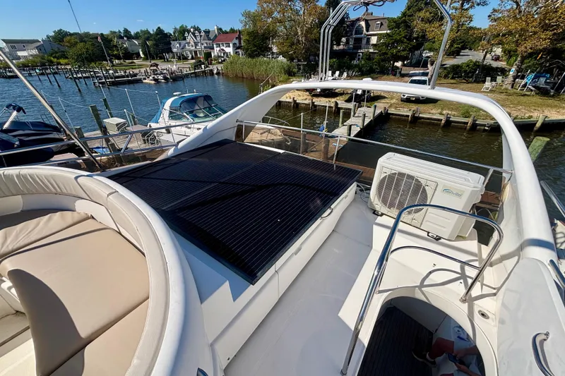 Slide: The Image of 2004 Viking Princess 61 Fly Bridge yacht docked, featuring spacious seating and solar panels. - 10