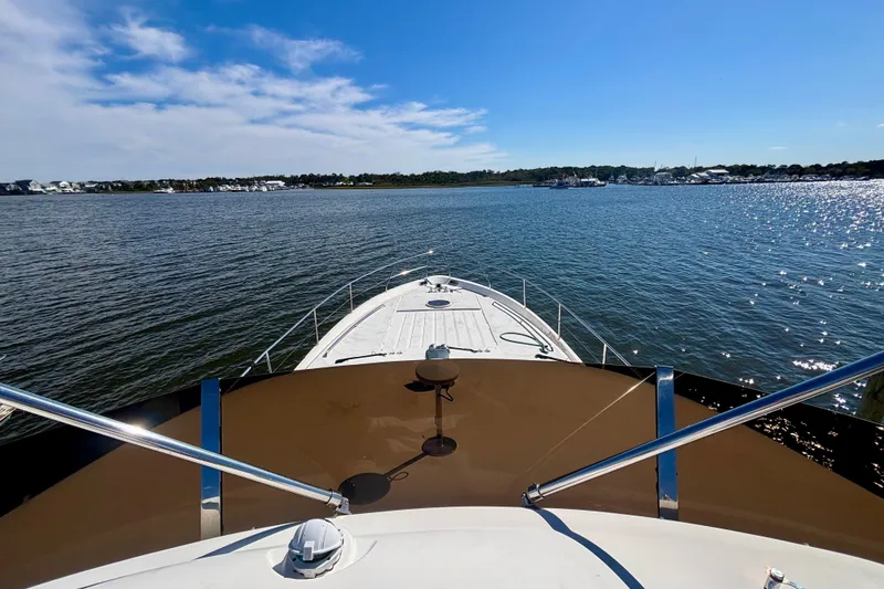Slide: The Image of 2004 Viking Princess 61 Fly Bridge yacht on calm waters under a clear blue sky. - 16