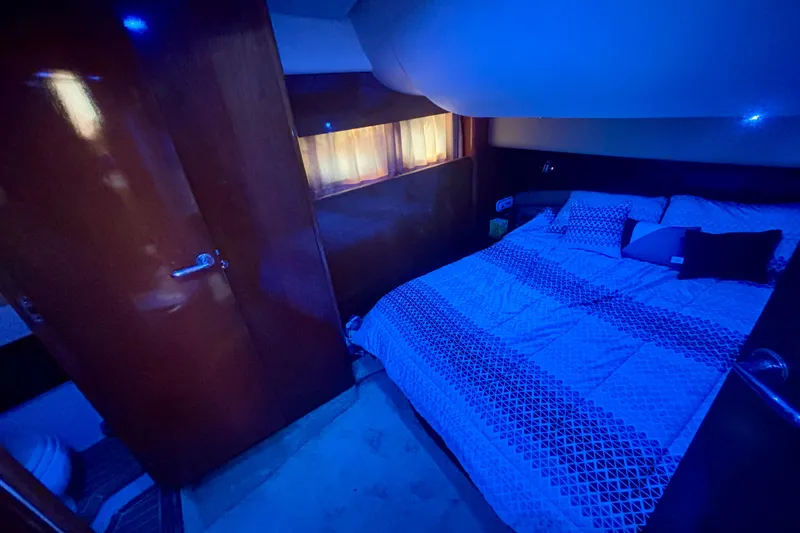 Slide: The Image of Luxurious bedroom interior of 2004 Viking Princess 61 Fly Bridge yacht, featuring ambient blue lighting. - 48