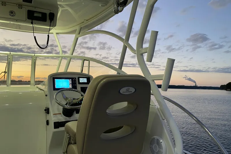 Slide: The Image of 2020 Sailfish 270 WAC boat interior at sunset, featuring navigation equipment and serene water view. - 11