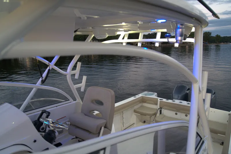 Slide: The Image of 2020 Sailfish 270 WAC boat interior with seating and steering, docked by calm waters. - 14