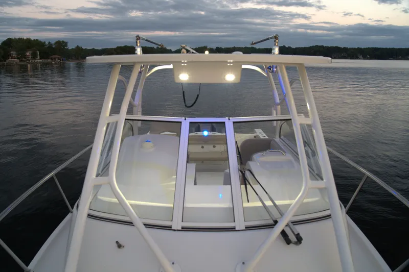 Slide: The Image of 2020 Sailfish 270 WAC boat on calm water at dusk, featuring illuminated deck. - 17