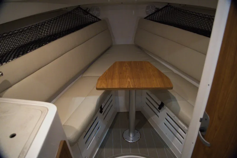 Slide: The Image of 2020 Sailfish 270 WAC cabin interior with beige seating and wooden table. - 22
