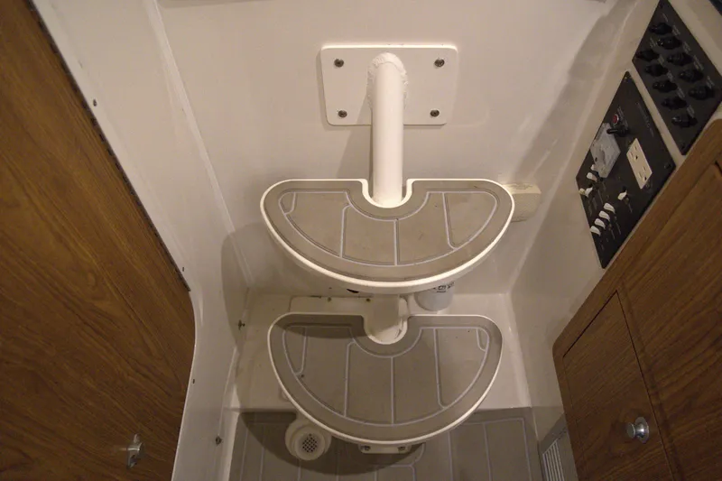 Slide: The Image of Interior of 2020 Sailfish 270 WAC boat showing compact bathroom steps and control panel. - 23